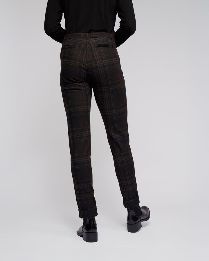 Someone wearing Vassalli Style Pant - Hugo, black shoes, and a long-sleeve black top stands with their back to the camera against a plain light background.