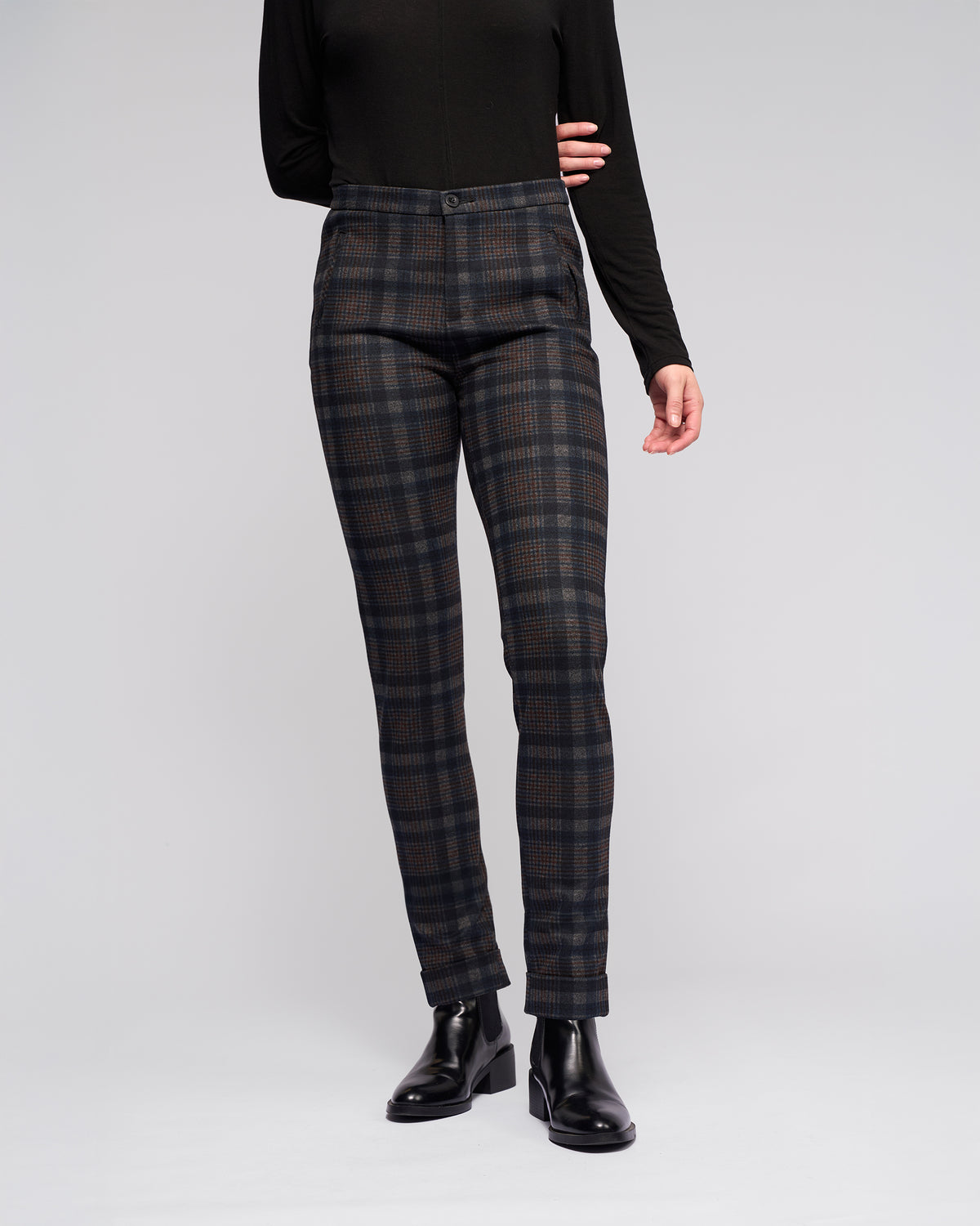 A person models Vassalli's Style Pant - Nomad with a long-sleeve black top and black ankle boots against a plain light gray background. Their face is not visible.