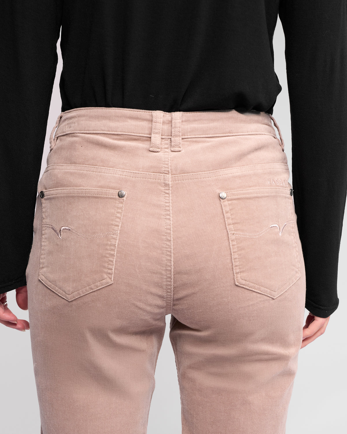 Model shown from the back wears a black long-sleeve shirt and Vassalli Arch Cord Pant - Twig, highlighting pockets and stitching on the stretch pinwale corduroy fabric.