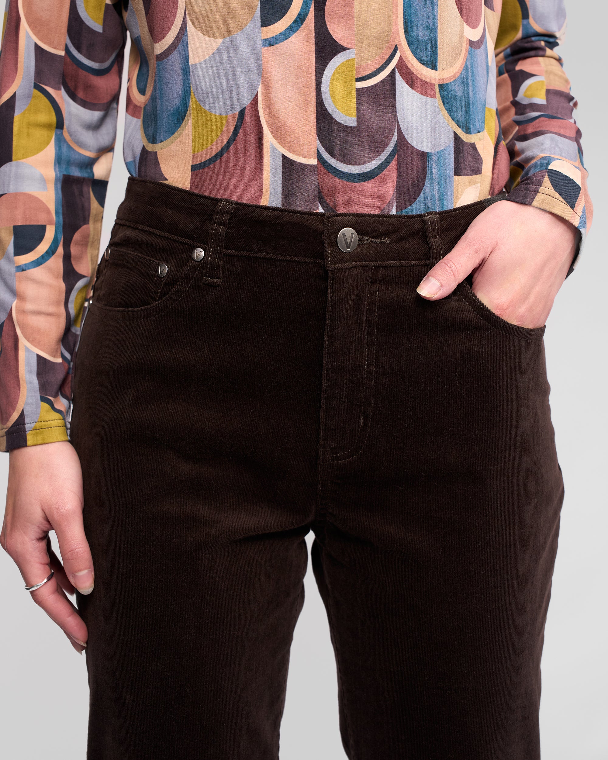 A person wearing Vassalli's Arch Cord Pant in Walnut, with one hand in their pocket, shown from waist to mid-thigh against a neutral background.