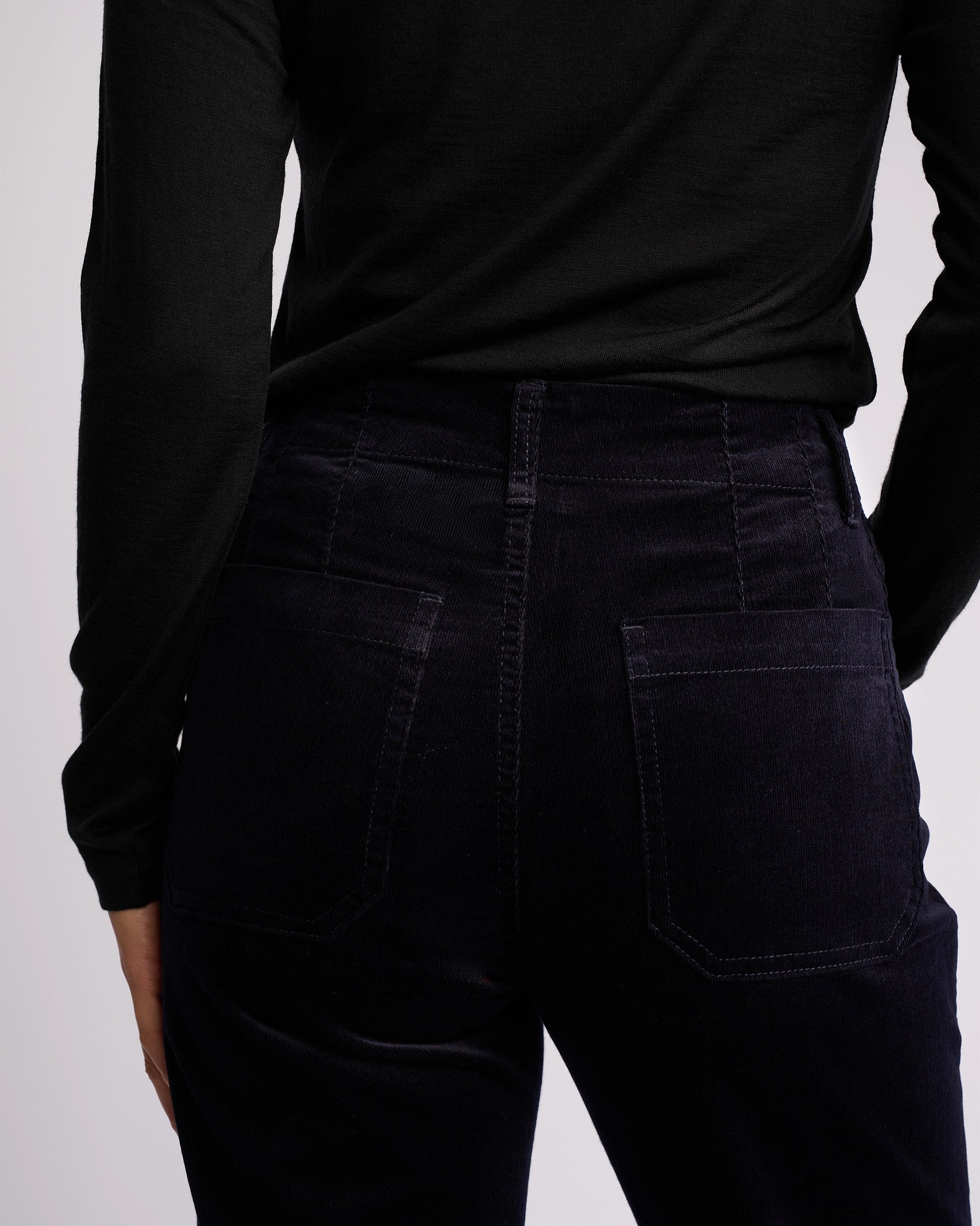 A person is shown from the back wearing Vassalli's Daily Cord Pant in Midnight, with the focus on the waist and hip area.