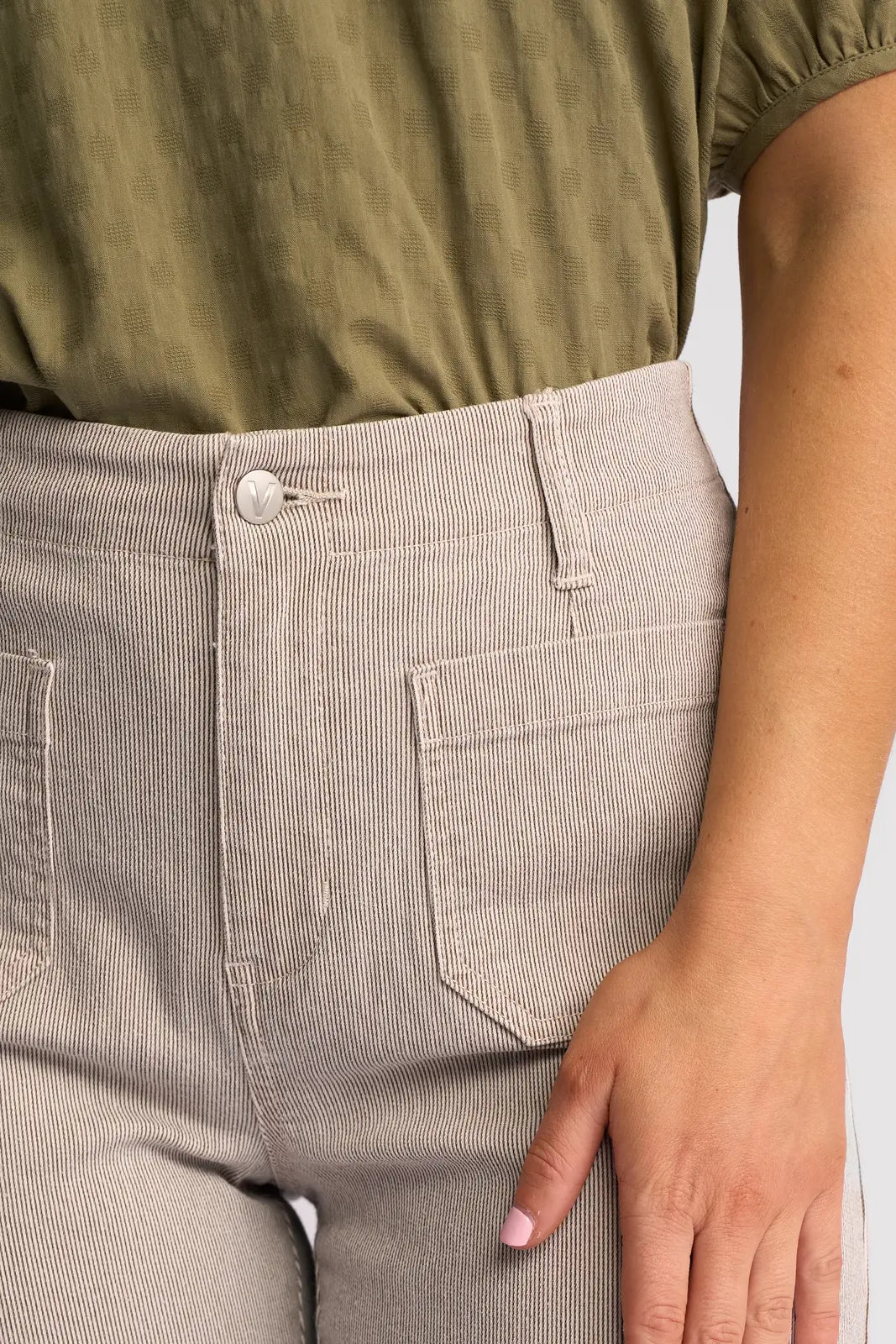 A person wearing a textured green shirt tucked into Vassalli’s Daily Jean in Ecru Stripe Denim, featuring high-waisted, light beige pinstripe denim with visible front pockets, shown from waist to mid-thigh.