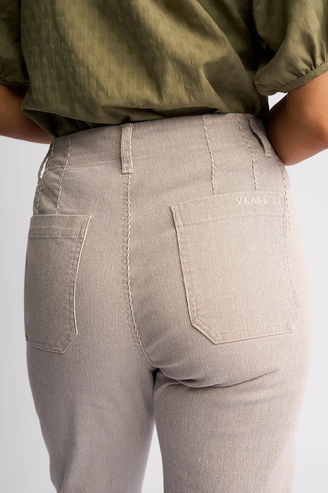 A person is shown from the waist down, facing away from the camera, wearing Vassalli’s Daily Jean in Ecru Stripe Denim, highlighting the rear pockets and fabric details of the jeans.