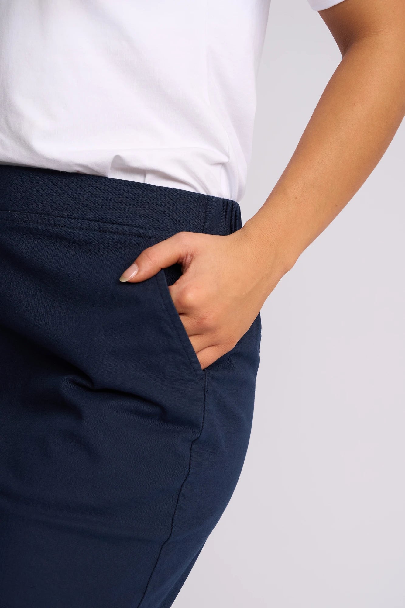A person wearing a white shirt and a Vassalli Belen Skirt - Ink has their right hand in the skirt pocket. Only the lower torso and arm are visible against a plain background.
