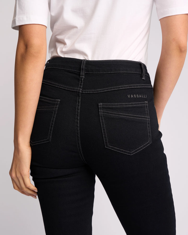 A person is shown from the back wearing a white shirt and Vassalli Studio Jean - Black Denim, featuring white stitching, two back pockets, and 'Vassalli' embroidered above the right pocket.