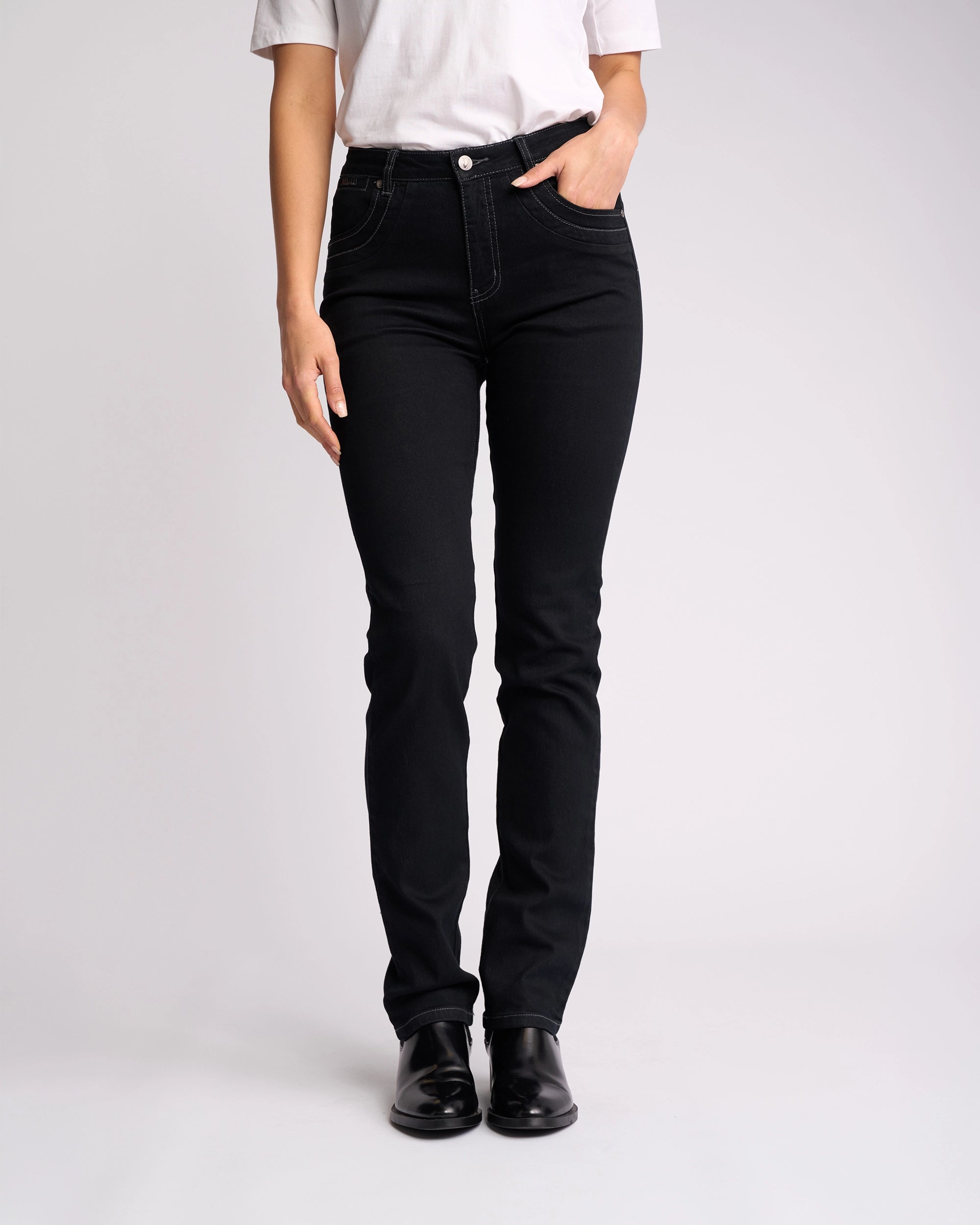 Someone stands against a plain white background wearing a white t-shirt, Vassalli Studio Jean - Black Denim, and black shoes, with one hand in their pocket.