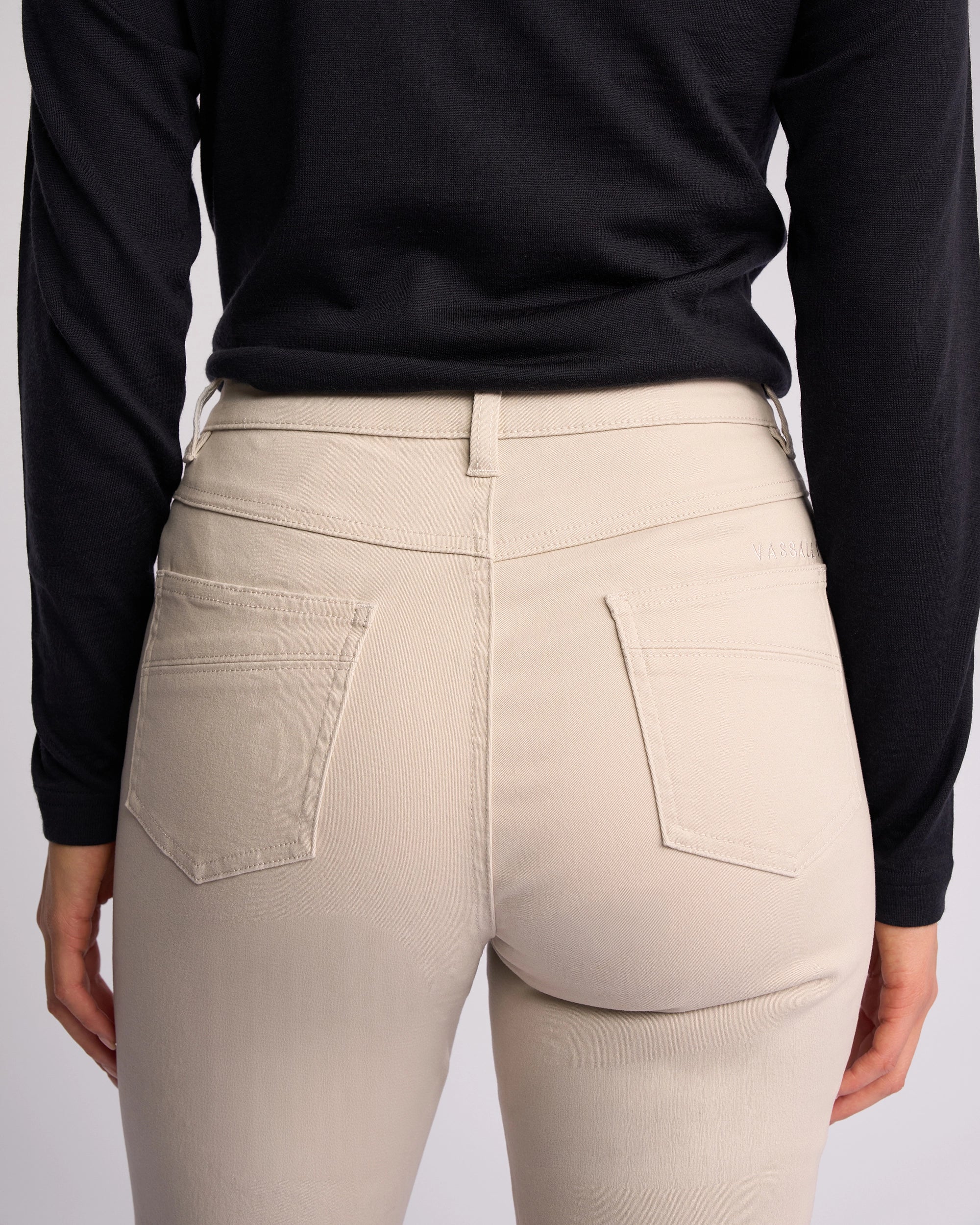A person is seen from the back wearing Vassalli Studio Jean - Pumice, highlighting the waist, upper legs, and visible back pockets.