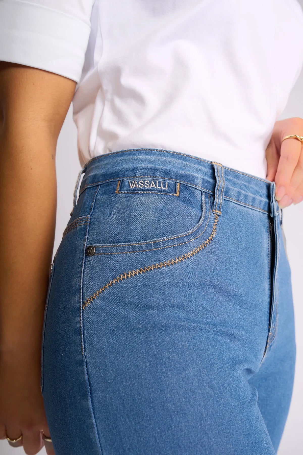 Close-up of a person wearing the Vassalli Custom Short in Light Denim paired with a white T-shirt. These high-waisted shorts, ideal for summer, feature a Vassalli label above the right front pocket. The person’s right arm is partially visible along their side.