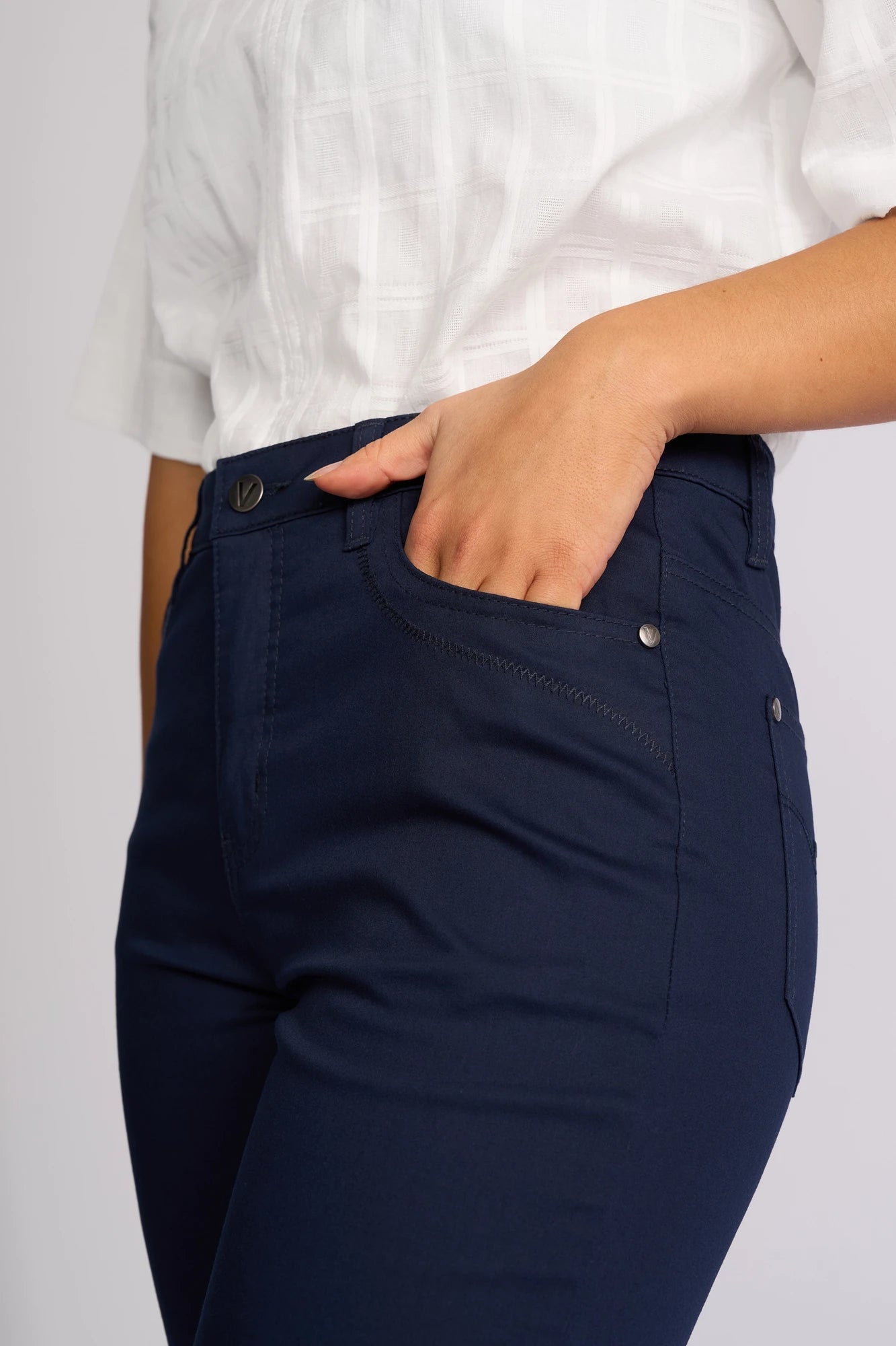 A person wearing a white short-sleeve shirt and Vassalli Custom Lightweight Short in navy stands with one hand in their pocket, facing slightly to the side.