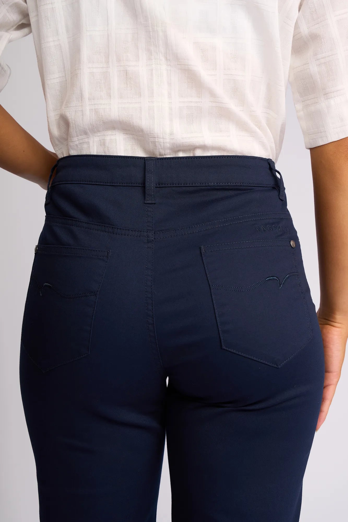 A person is shown from the waist down and from behind wearing a white short-sleeve textured shirt paired with Vassalli’s Custom Lightweight Short in Navy, featuring visible back pockets.