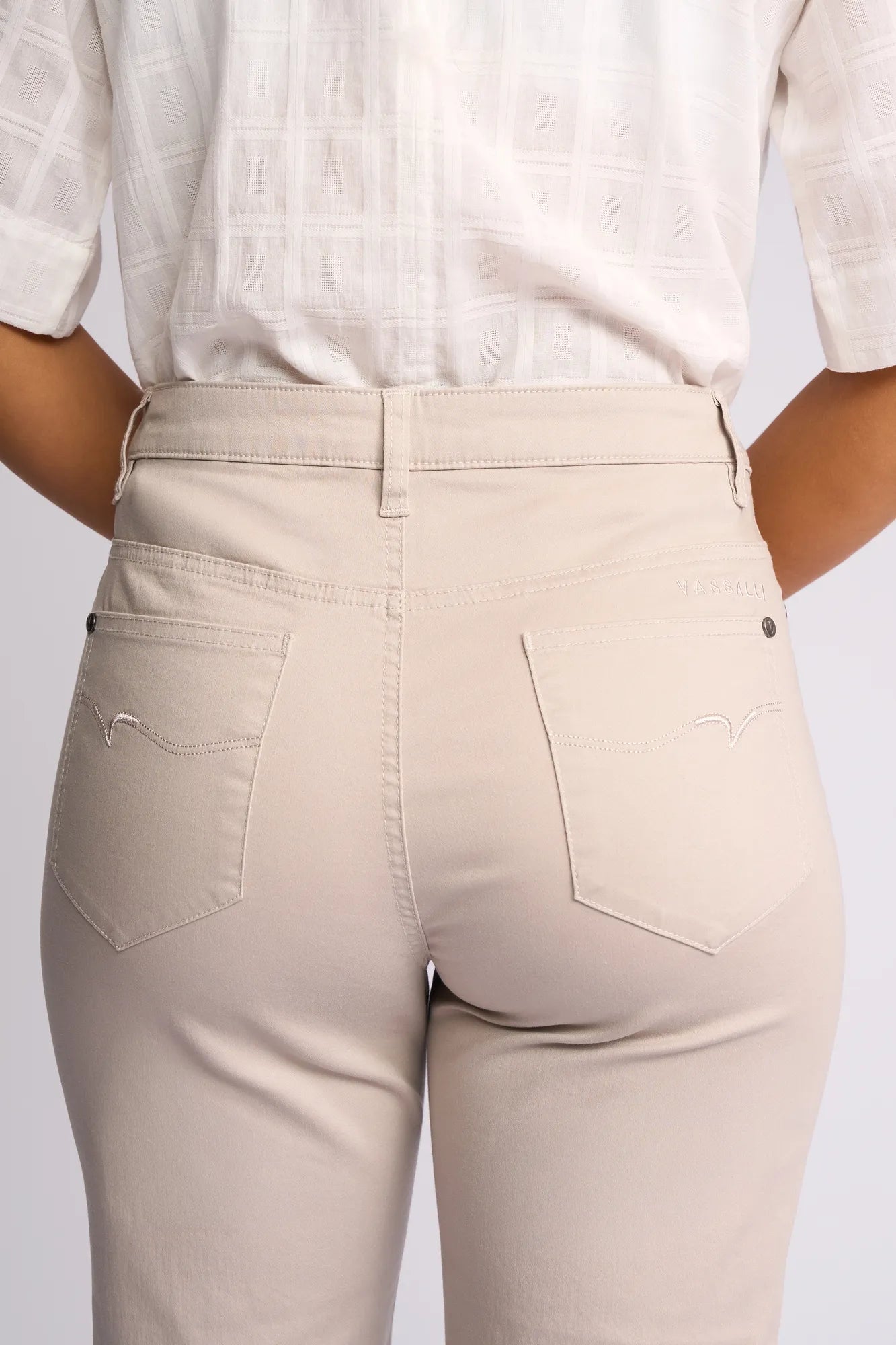 A person is shown from the back wearing Vassalli’s Custom Lightweight Short in Pumice—a stylish, practical option for summer crafted from a comfortable cotton-elastane blend. The shorts feature two back pockets with subtle stitching, and are paired here with a white patterned shirt, highlighting the waist and hip area.