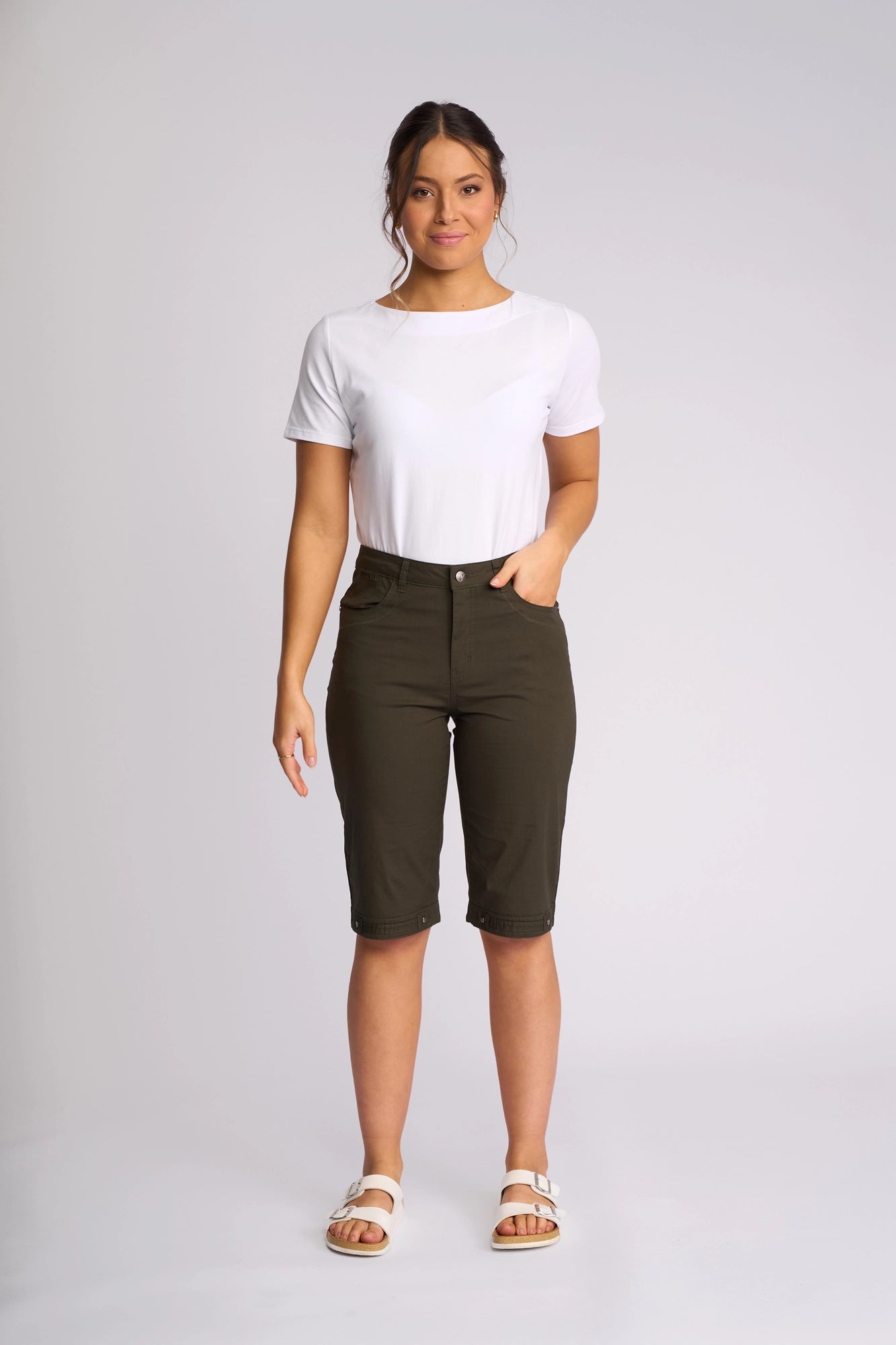 A woman stands facing forward, wearing a white t-shirt, Vassalli Custom Poplin Short in khaki with a straight-leg fit, and white sandals, against a plain light background.