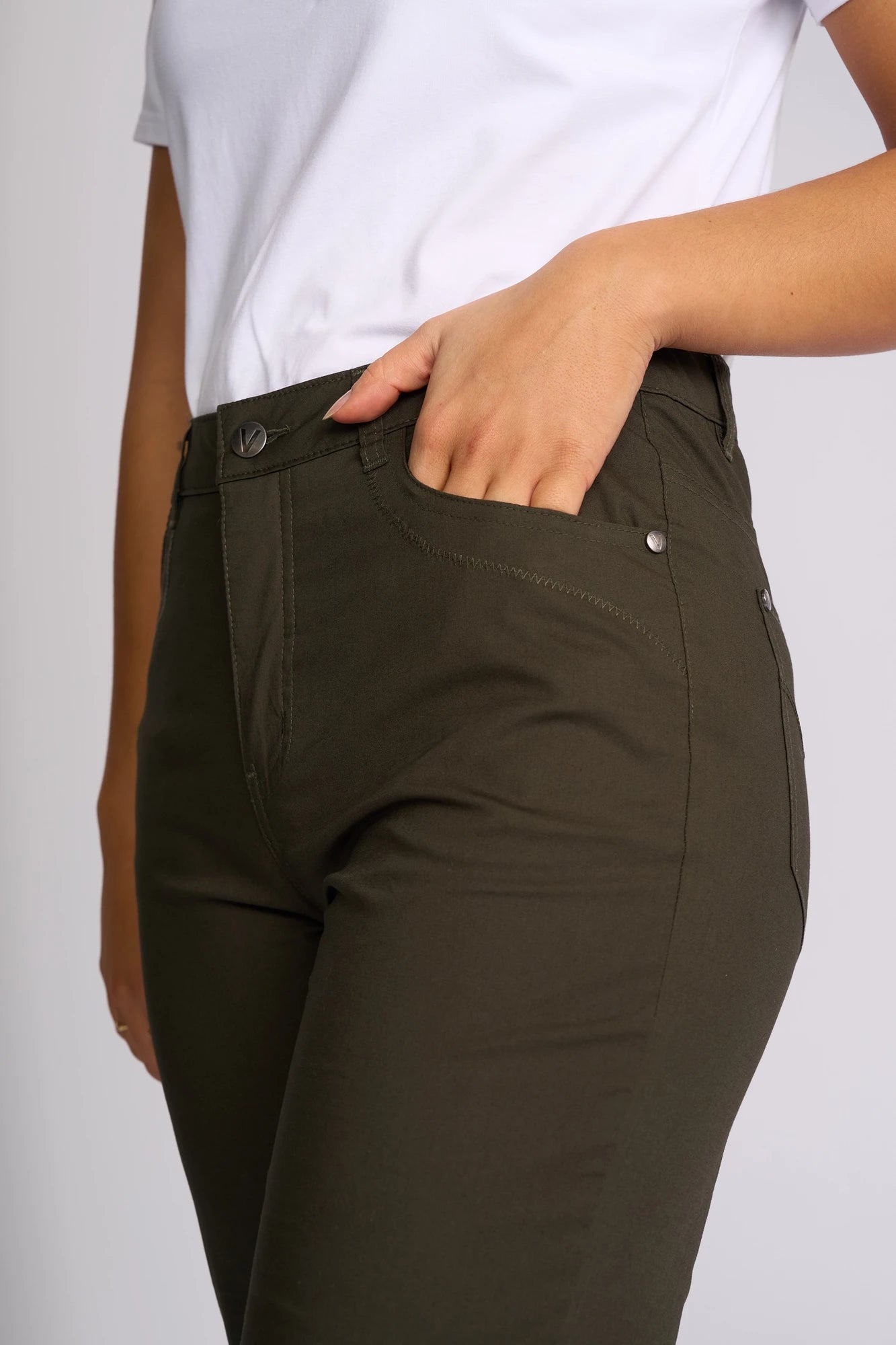 A person wearing a white shirt and Vassalli Custom Poplin Short in khaki, with one hand in their pocket, is shown from mid-torso to upper thigh against a plain background.