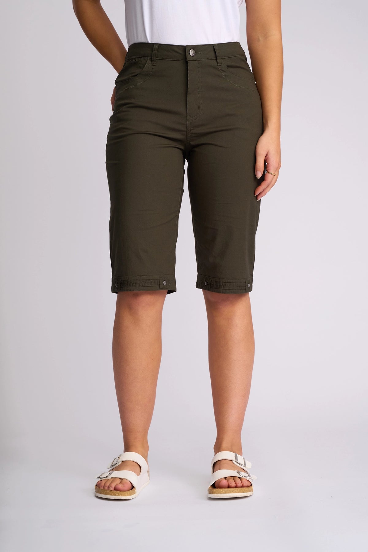 A person wearing Vassalli’s Custom Poplin Short in Khaki, paired with a white shirt and white sandals, stands against a plain light background.
