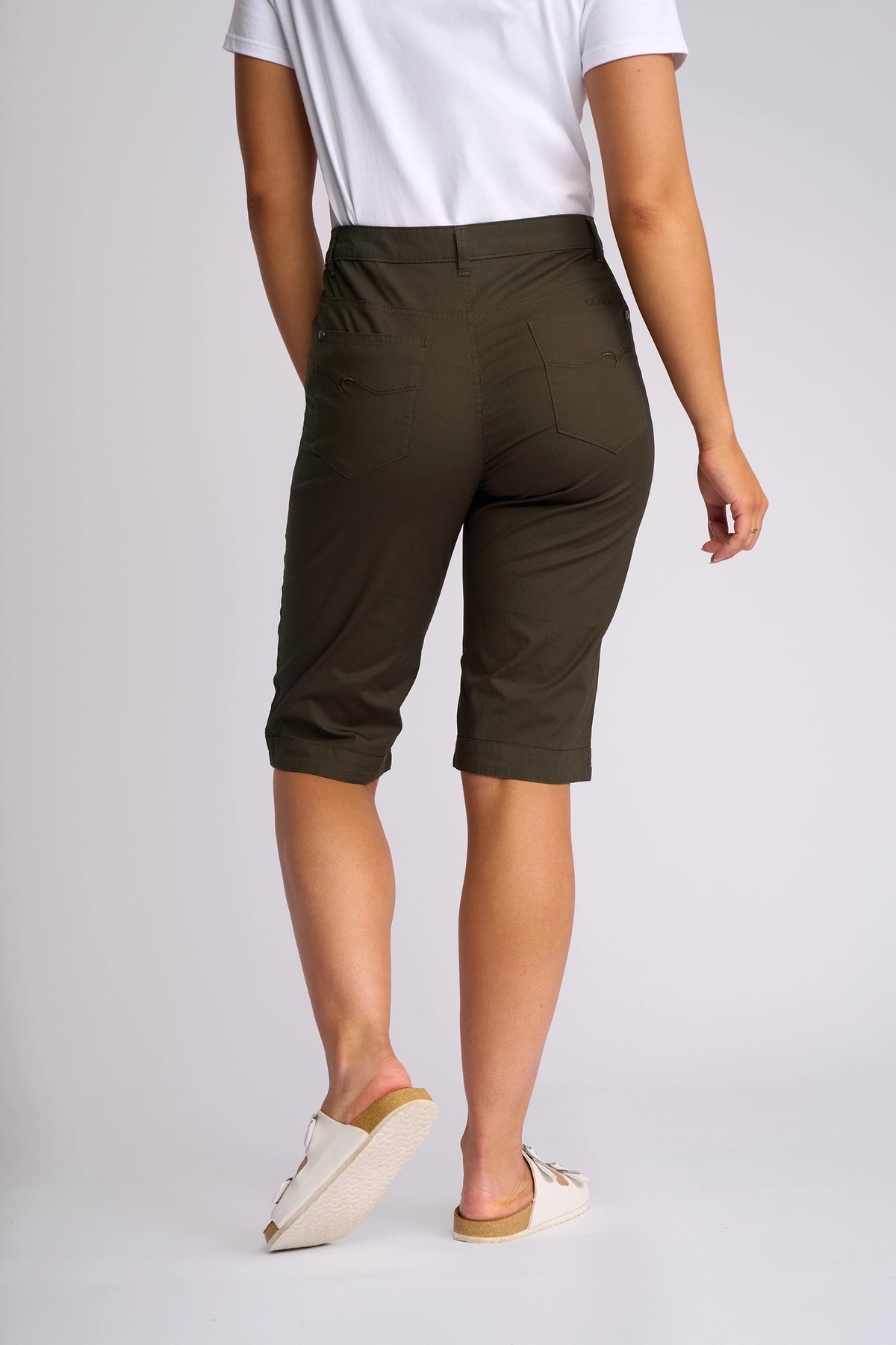 A person wearing a white T-shirt, Vassalli Custom Poplin Short in Khaki, and white slip-on shoes is standing with their back to the camera against a plain background.
