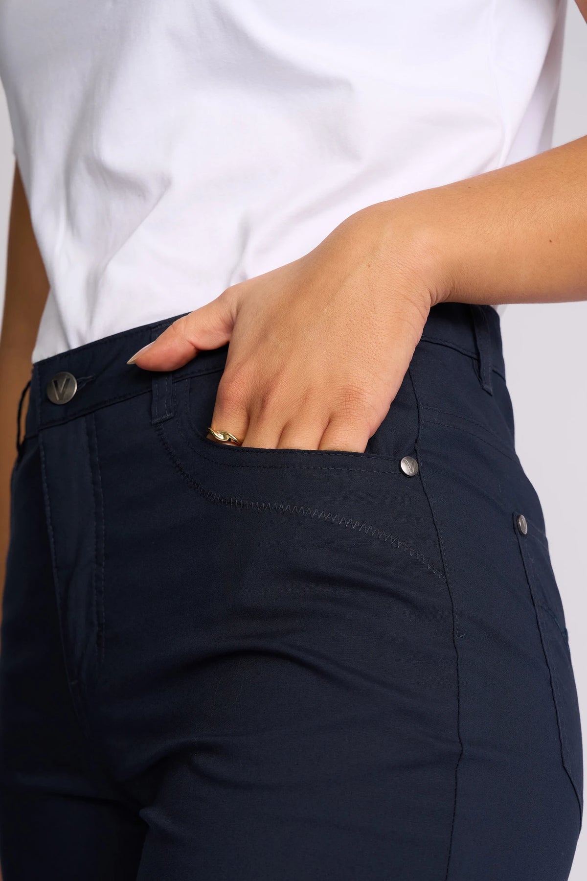 Wearing a white shirt and Vassalli’s Custom Poplin Short in Navy, the person places their right hand in their shorts pocket, drawing attention to a gold ring on their finger.