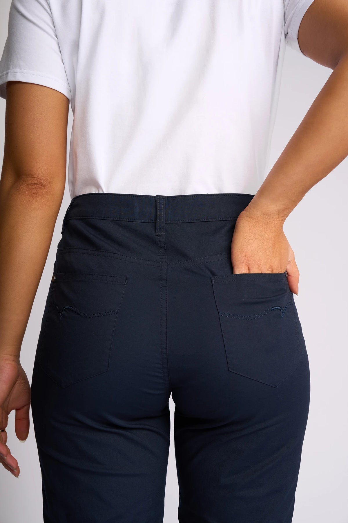 A person wearing a white t-shirt and the Vassalli Custom Poplin Short in Navy is shown from the back, with one hand resting in their pocket against a plain background.