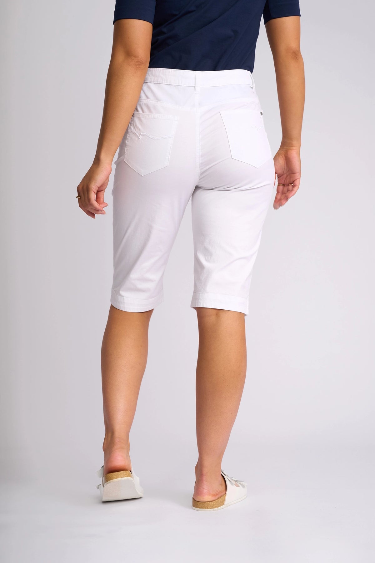 A person wearing a navy shirt, the Vassalli Custom Poplin Short in white—a classic summer staple—and white shoes stands facing away, highlighting the back of the shorts with two pockets.